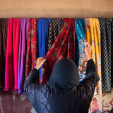 Iraqi Woman selecting fabric from a wall
